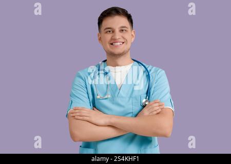 Junger glücklicher männlicher Zahnarzt auf lila Hintergrund Stockfoto