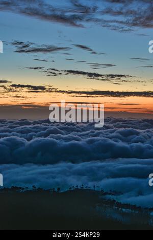Spektakuläre Wolkenumkehr über dem Atlantischen Ozean und Einzug in die Bergklippen nach Sonnenuntergang, Insel Madeira, Portugal. Stockfoto