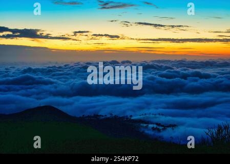 Spektakuläre Wolkenumkehr über dem Atlantischen Ozean und Einzug in die Bergklippen nach Sonnenuntergang, Insel Madeira, Portugal. Stockfoto