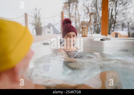 Seniorenpaar baden im Wannen-Whirlpool an kalten Wintertagen. Romantischer Wellness-Kurzurlaub mit Spa am Valentinstag-Wochenende. Stockfoto