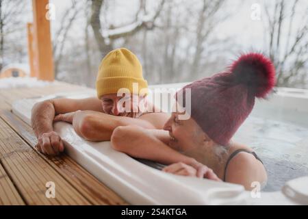 Seniorenpaar baden im Wannen-Whirlpool an kalten Wintertagen. Romantischer Wellness-Kurzurlaub mit Spa am Valentinstag-Wochenende. Stockfoto