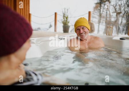 Seniorenpaar baden im Wannen-Whirlpool an kalten Wintertagen. Romantischer Wellness-Kurzurlaub mit Spa am Valentinstag-Wochenende. Stockfoto
