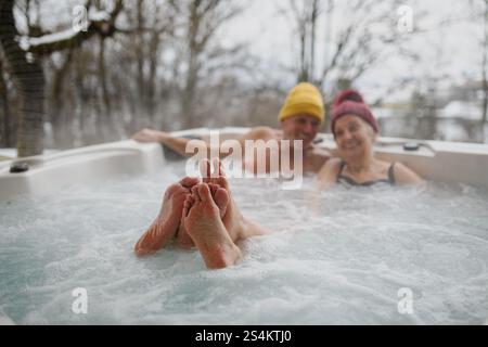 Schließen Sie sich den Füßen eines Seniorenpaares an, das an kalten Wintertagen im Wannen-Whirlpool badete. Stockfoto