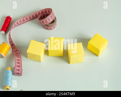 Hintergrund zum Nähen. Gelbe leere Papierwürfel auf hellem Hintergrund Stockfoto