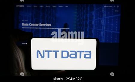 Deutschland. Oktober 2024. In dieser Abbildung hält eine Person ein Mobiltelefon mit dem Logo des japanischen IT-Unternehmens NTT DATA Corporation auf dem Bildschirm vor der Unternehmenswebseite. Quelle: SOPA Images Limited/Alamy Live News Stockfoto