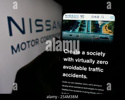 Deutschland. Oktober 2024. In dieser Abbildung hält eine Person ein Smartphone mit der Webseite des japanischen Unternehmens Nissan Motor Corporation auf dem Bildschirm vor dem Logo. Quelle: SOPA Images Limited/Alamy Live News Stockfoto