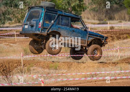 Der Nervenkitzel des Offroad-Rennens. Ein modifizierter SUV wird mitten in der Luft gefangen und schwingt über einen Schottersprung. Stockfoto