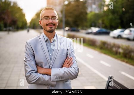 Porträt eines jungen Geschäftsmannes, der auf der Straße steht, auf Distanz blickt und lächelt. Stockfoto