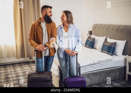 Das junge glückliche Paar ist im Urlaub. Touristen kamen mit ihren Koffern im Hotelzimmer an. Stockfoto
