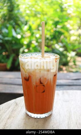 Ein Glas süßer und cremiger Thai Iced Tea auf dem Gartentisch Stockfoto