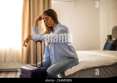 Die Touristenin kam mit ihrem Koffer im Hotelzimmer an. Sie hat genug von Reisen und braucht Ruhe. Stockfoto