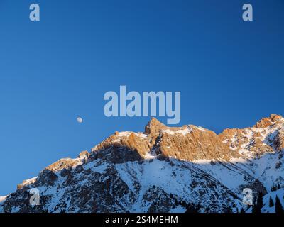 Blick auf einen Berggipfel, beleuchtet von der Abendsonne. Schönes klares Winterwetter in den Bergen Stockfoto