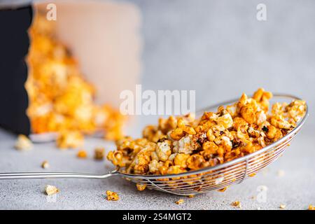 Gourmet süßes Karamell Popcorn in einem glänzenden Drahtkorb, die in Karamell getauchten zuckergoldenen Stücke sitzen verführerisch vor einem neutralen grauen Hintergrund. Stockfoto