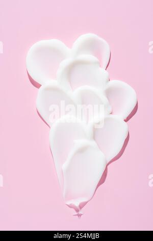 Elegantes Farbmuster mit weißer Creme- oder Gel-Textur, isoliert auf einem leuchtend rosa Hintergrund, ein ideales Bild für Hautpflege- und Schönheitskonzepte. Stockfoto