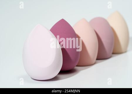 Eine Reihe weicher Kosmetikschwämme in Farbverläufen, einschließlich weiß, Rosa und Beige, ideal für makelloses Make-up, perfekt für Schönheit und Haut Stockfoto