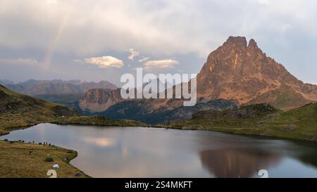 Panoramablick auf den Gipfel Midi d'Ossau, der sich in einem ruhigen See spiegelt, umgeben von üppiger Vegetation in den französischen Pyrenäen, Eine ruhige Landschaft, die perfekt ist Stockfoto