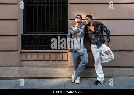 Ein lateinamerikanisches Schwulenpaar genießt das sonnige Wetter in Madrid und strahlt Glück und Authentizität aus. In einer lebhaften urbanen Umgebung sind ihre lässigen Outfits und die perfekte Wahl Stockfoto