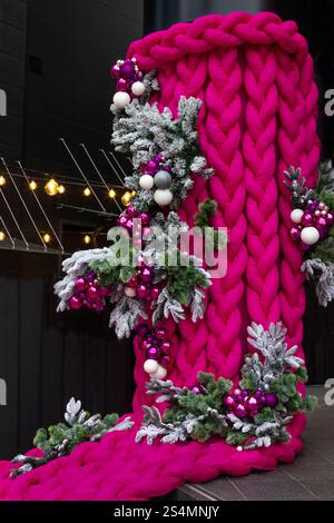 Weihnachtsdekoration draußen. Geflochtene pinkfarbene Stoffgeflechte. Tannenzweige und farbige Kugeln. Stockfoto