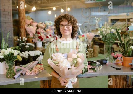 Hochwinkelaufnahme eines attraktiven Blumenhandels mit wunderbarem Blumenstrauß aus Rosen und eingewickelt in pastellrosa Geschenkpapier Stockfoto