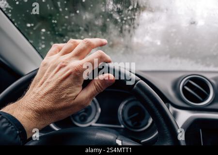 Männliche Hand am Autolenkrad an kalten Wintertagen, selektiver Fokus Stockfoto