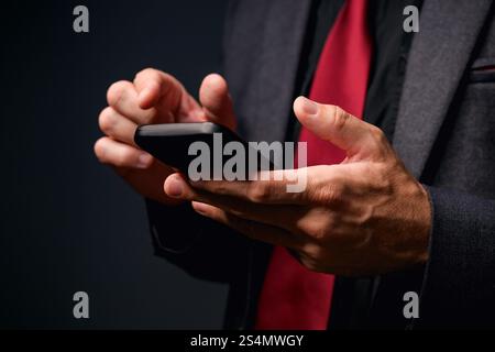 E-Commerce-Konzept, mobiles Banking oder elektronisches Geschäft, Geschäftsmann mit Smartphone im dunklen Büro, Low-Key mit selektivem Fokus Stockfoto