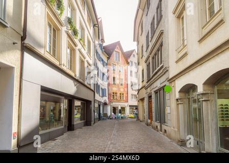 Eine gepflasterte Fußgängerzone, gesäumt von traditionellen Bürgerhäusern und Geschäften in Chur, Schweiz, bei Sonnenuntergang im Sommer Stockfoto