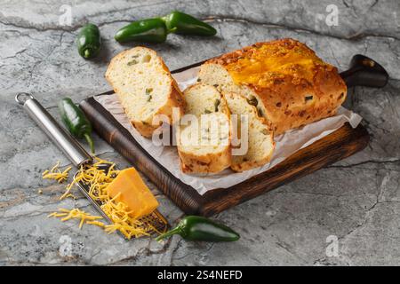 Hausgemachtes knuspriges Jalapeno-Käsebrot in dicke Scheiben geschnitten Nahaufnahme auf dem Schneidebrett auf dem Tisch. Horizontal Stockfoto