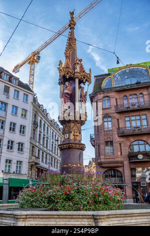 Fischmarktbrunnen - Fischmarktbrunnen in Basel, Schweiz. Gotischer Brunnen aus dem Jahr 1380, zentrale Säule mit Figuren der Jungfrau Maria, des heiligen Haustieres Stockfoto