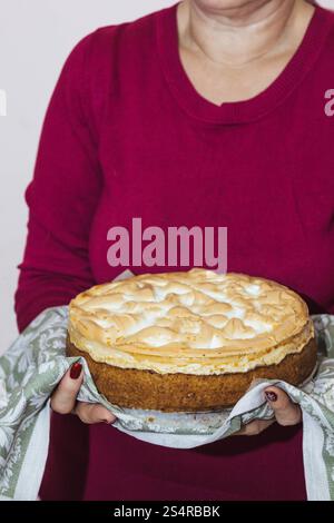 Die Großmutter hält einen ganzen Teller mit einem riesigen Kuchen in den Händen, ein traditionelles Essen auf dem Land. Von oben fotografiert. Stockfoto