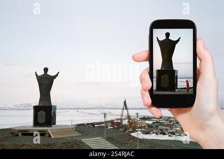 Reisen Sie Konzept - Touristen nehmen Foto Denkmal Nikolaus auf Andyrsky Liman in Tschukotka auf mobile Gadget, Anadyr, Russland Stockfoto