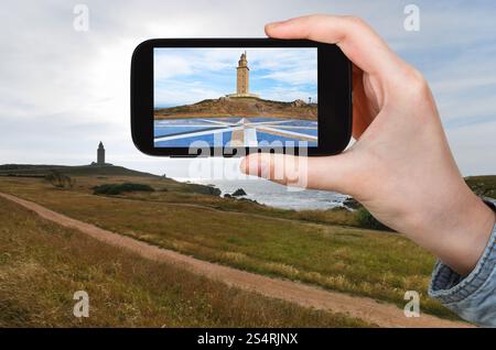 Reisekonzept - Touristen fotografieren das antike römische Denkmal - Leuchtturm des Herkules, La Coruna, Galicien, Spanien mit mobilen Geräten Stockfoto