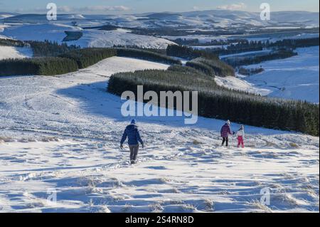 Winterwanderer, die von Muckle Knock in den Southern Pentland Hills in der Nähe von Baddinsgill, Schottland, absteigen Stockfoto