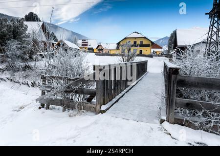Alte kleine Holzbrücke über Gebirgsfluss in Alpen am verschneiten Tag Stockfoto