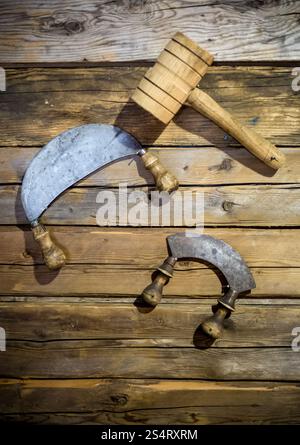 Nahaufnahme Foto von altes traditionelles Messer und Holzhammer an Wand Stockfoto