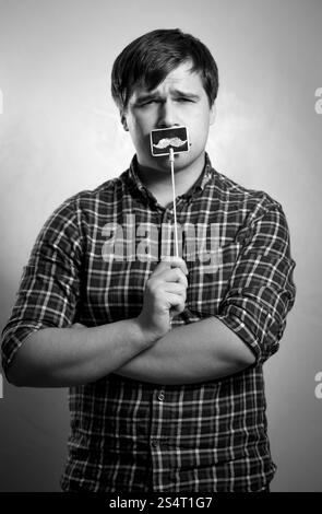 Schwarz-weiß-Porträt von junge Hipster Kerl posiert mit gefälschte Schnurrbart Stockfoto