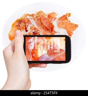 Fotografieren Essenskonzept - Tourist nimmt Bild italienischer geschnitten Schinken Prosciutto di Parma auf Smartphone, Italien Stockfoto