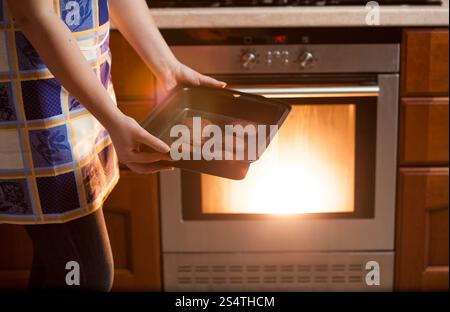 Nahaufnahme Foto Frau setzen Cookies im Ofen Stockfoto