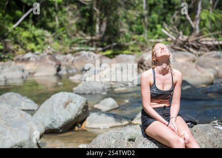 Rio Grande, Puerto Rico - 6. März 2018: Junge Frau sonnt sich in der Sonne am natürlichen Pool des Río Mameyes im El Yunque National Forest. Stockfoto