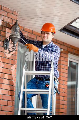 Junger Mann ändern Lampe am Außenleuchte Stockfoto
