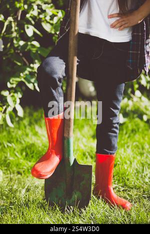 Closeup getönten Foto der jungen Frau mit Bein in Gummistiefeln auf Schaufel im Garten Stockfoto
