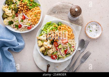Vegane Lunch Bowl mit Linsen, geröstetem Gemüse und Kichererbsen, Perle Couscous Salat mit Tomaten und Gurken, gesunde Lunch Idee Stockfoto