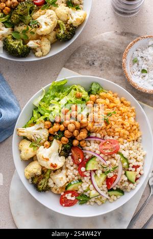 Vegane Lunch Bowl mit Linsen, geröstetem Gemüse und Kichererbsen, Perle Couscous Salat mit Tomaten und Gurken, gesunde Lunch Idee Stockfoto