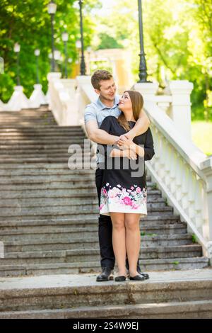 Wunderschönes verliebtes Paar, das sich auf Steintreppen im Park umarmt Stockfoto