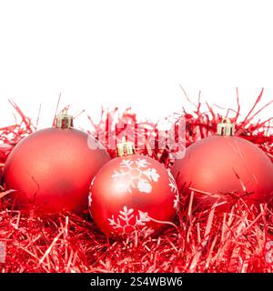 drei rote Christbaumkugeln und Lametta isoliert auf weißem Hintergrund Stockfoto
