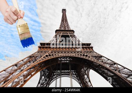 Reisekonzept - Hand mit Pinsel Farben blaue Himmel über den Eiffelturm in Paris City, Frankreich Stockfoto