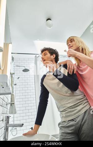 Glückliches Paar putzt sich gerne die Zähne und lacht in einem stilvollen Badezimmer. Stockfoto