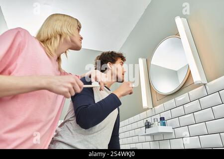 In einem fröhlichen Badezimmer genießen zwei Männer eine Morgenroutine, gemeinsam Lächeln und Lachen. Stockfoto