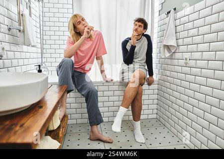 Zwei Männer genießen eine ruhige Zeit in einem stilvollen Badezimmer, teilen gemeinsam Gedanken und lachen. Stockfoto