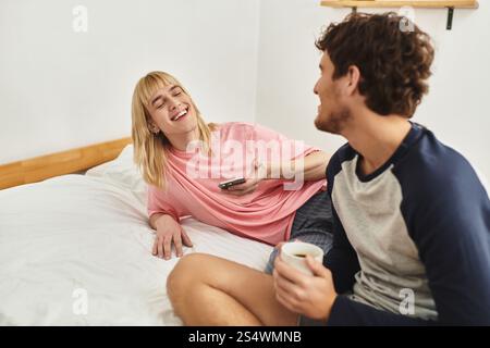 Zwei Männer teilen fröhliche Ausdrücke, während sie sich auf einem Bett entspannen und sich gegenseitig in Gesellschaft genießen. Stockfoto