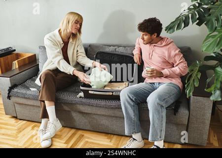 Zwei Männer teilen freudige Momente, während sie in einem stilvollen Raum die wichtigsten Dinge für ihre bevorstehende Reise packen. Stockfoto
